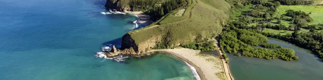 Vue aérienne de la Roche Percée à Bourail, avec sa plage au premier plan, la baie des Tortues et le sentier des Trois Baies.