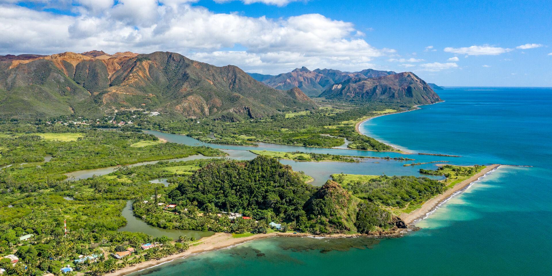 Vue aérienne sur la commune de Thio, en Nouvelle-Calédonie, avec vue sur le belvédère du Bota Méré, le village et les montagnes.