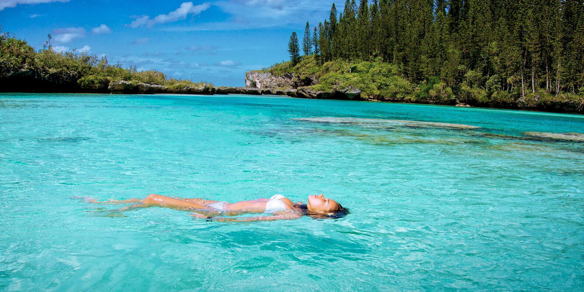 Relax at the Piscine naturelle d'Oro with its crystal-clear water, surrounded by columnar pines on Île des Pins, New Caledonia.