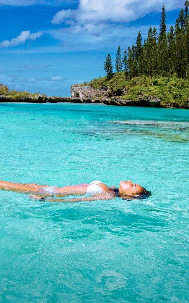 Relax at the Piscine naturelle d'Oro with its crystal-clear water, surrounded by columnar pines on Île des Pins, New Caledonia.