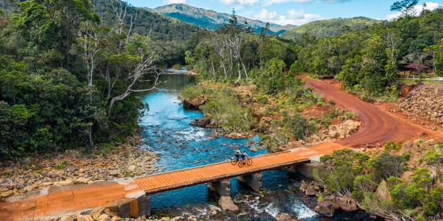 Traversée d'un pont en VTT au Parc Provincial de la Rivière Bleue à Yaté, dans le Grand Sud de la Nouvelle-Calédonie.