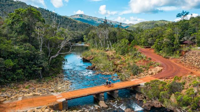 Crossing a bridge on a mountain bike in the Rivière Bleue Provincial Park in Yaté, New Caledonia.