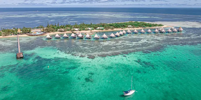 Aerial view of DoubleTree by Hilton at Îlot Maître, with its overwater bungalows above the lagoon near Nouméa.