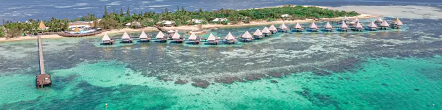 Vue aérienne du DoubleTree by Hilton à l’îlot Maître, avec ses bungalows sur pilotis au-dessus du lagon près de Nouméa.