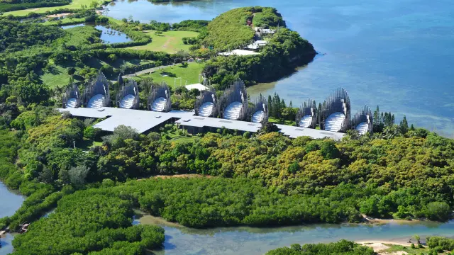 Vue aérienne du Centre culturel Tjibaou à Nouméa, entre mangrove, végétation tropicale et lagon.