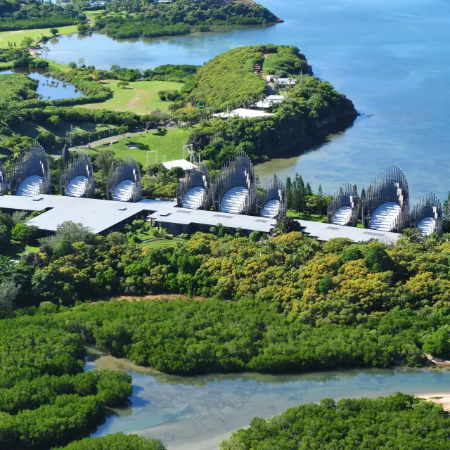 Vue aérienne du Centre culturel Tjibaou à Nouméa, entre mangrove, végétation tropicale et lagon.