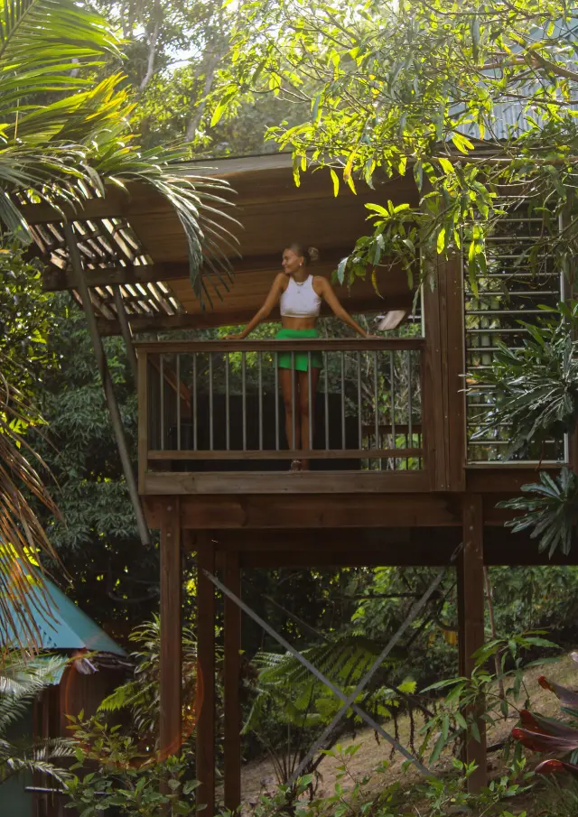 Voyageuse sur le balcon surélevé d’un hébergement du Ka Waboana Lodge à Hienghène, entourée d’une végétation tropicale luxuriante.