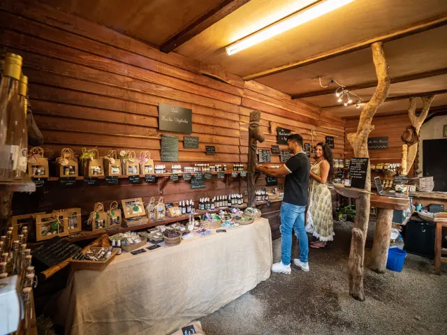 Deux visiteurs découvrent les produits artisanaux de la boutique de la distillerie de Boulouparis, dans un décor en bois.