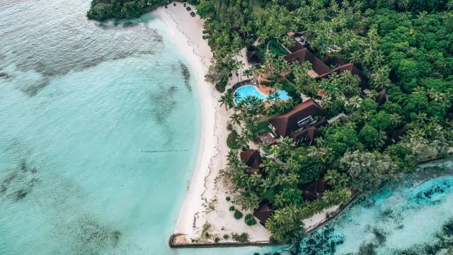 Vue aérienne sur Le Domaine Oro, Series by Marriott à l’Île des Pins, bordé par une plage de sable blanc, un lagon turquoise et une végétation tropicale.