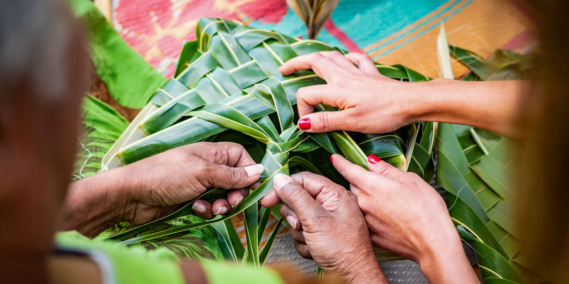 Des mains tressent des feuilles de pandanus pour réaliser un ouvrage artisanal, en Nouvelle-Calédonie.