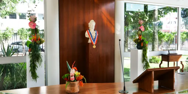 Official ceremony area in the wedding room at Nouméa City Hall, with a wooden desk, microphone, floral arrangements and republican bust.