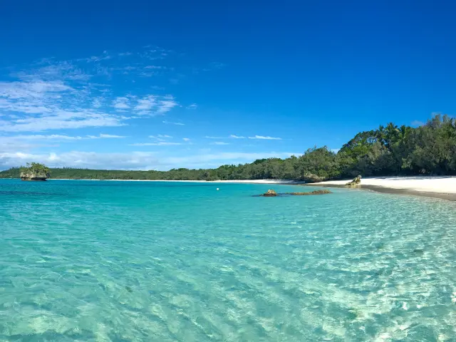 Vue sur la plage de Luengoni à Lifou, avec son lagon turquoise, son sable blanc et la végétation en bord de plage.