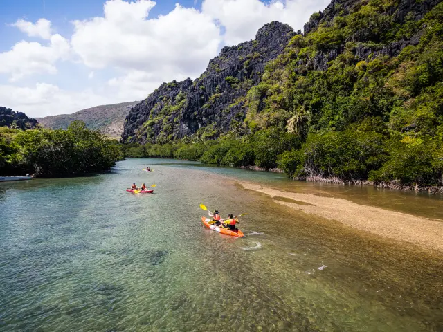Des kayakistes naviguent au pied des falaises de Lindéralique à Hienghène, entre eau claire, mangrove et formations rocheuses.