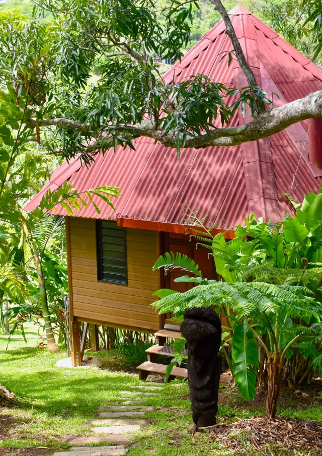Bungalow en bois du Lodge Terre de Soleil à Farino, entouré d’une végétation tropicale luxuriante avec fougères, bambous et arbres.