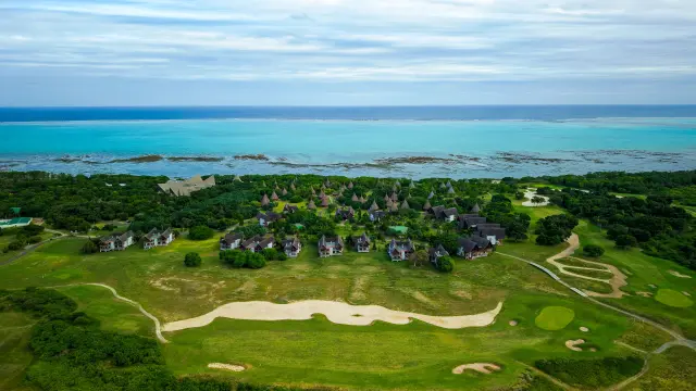 Vue aérienne du Domaine Déva à Bourail, avec le golf, les bungalows et le lagon de Poé en arrière-plan.