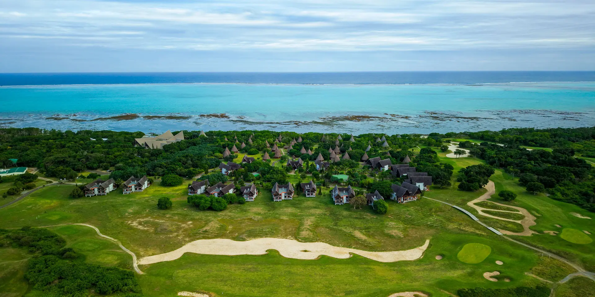 Aerial view of New Caledonia Deva Spa & Golf Resort in Bourail, with the golf course, bungalows and Poé Lagoon in the background.