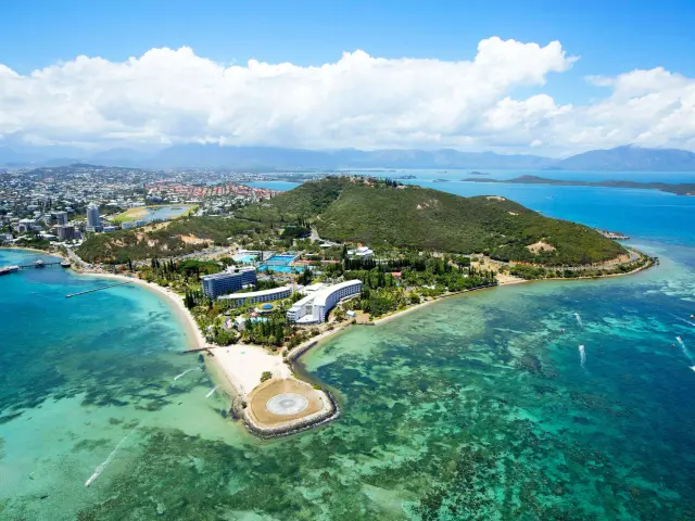 Aerial view of Nouméa Resort & Spa by the lagoon, with Anse Vata beaches, Nouméa peninsula and turquoise waters in the background.