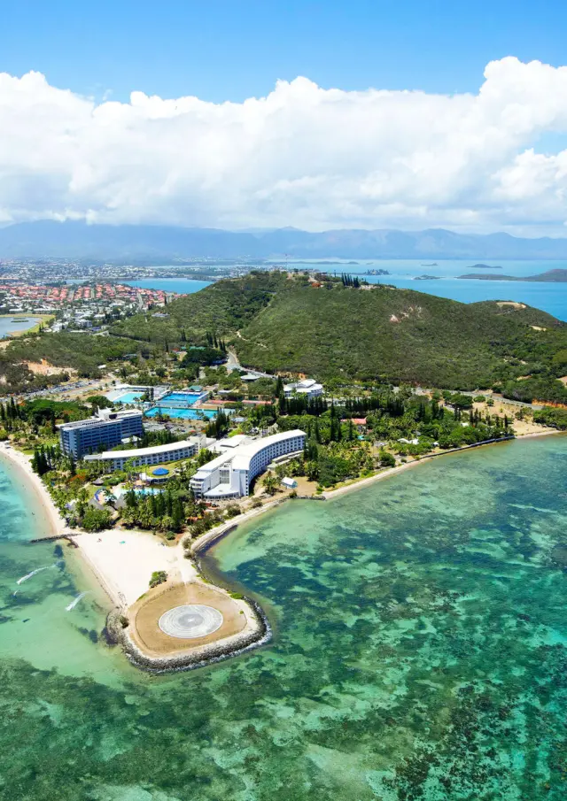 Aerial view of Nouméa Resort & Spa by the lagoon, with Anse Vata beaches, Nouméa peninsula and turquoise waters in the background.