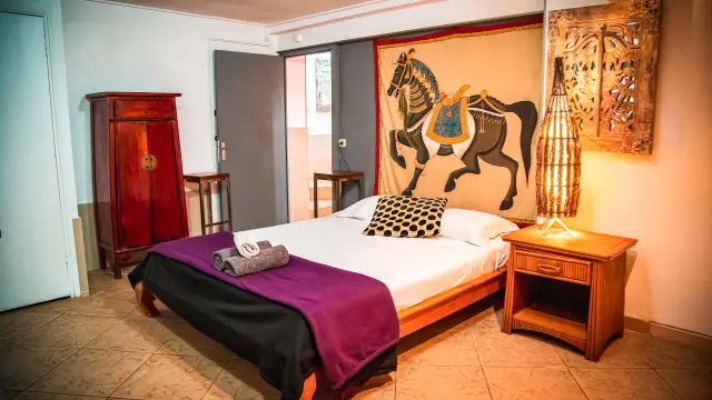 Chambre de la Résidence Marina Beach Hotel à Nouméa, avec lit double, mobilier en bois, décoration chaleureuse et tapisserie murale.