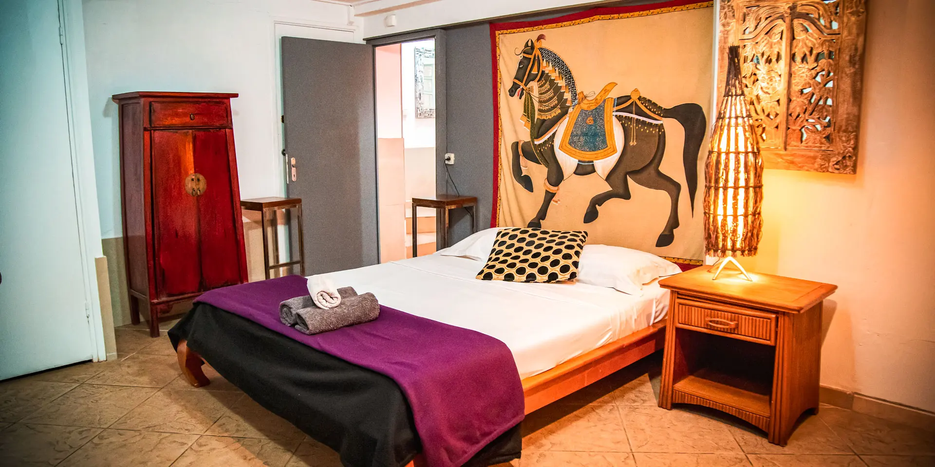 Chambre de la Résidence Marina Beach Hotel à Nouméa, avec lit double, mobilier en bois, décoration chaleureuse et tapisserie murale.