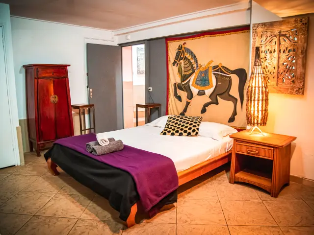 Chambre de la Résidence Marina Beach Hotel à Nouméa, avec lit double, mobilier en bois, décoration chaleureuse et tapisserie murale.